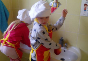 Dwoj chłopcy podczas mycia jabłek w łazience.